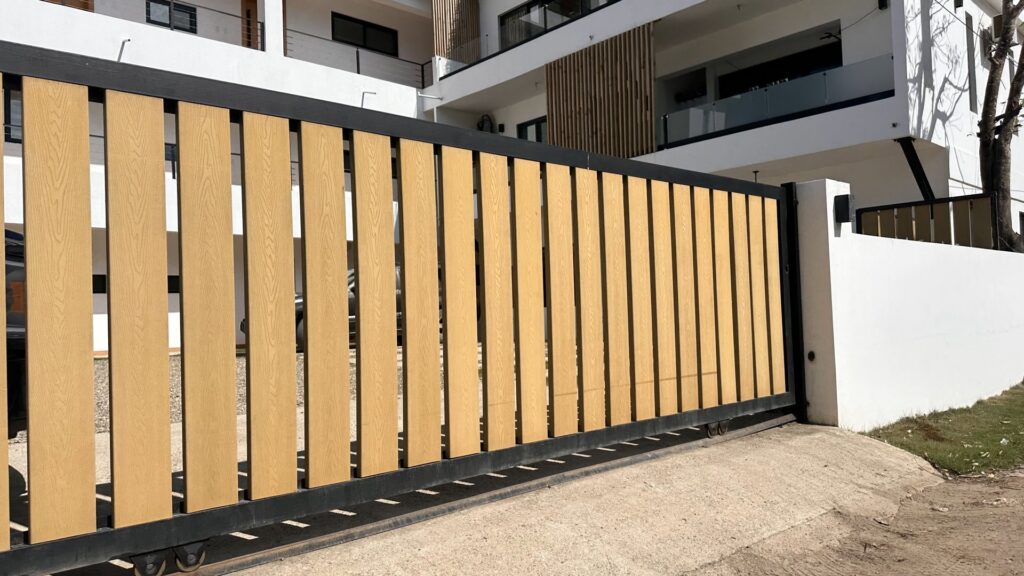 A modern sliding gate with wood-look slats and a black frame, installed by San Diego Fencing Contractor A's Pro Build Fencing in San Diego, CA.