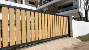 A modern sliding gate with wood-look slats and a black frame, installed by San Diego Fencing Contractor A's Pro Build Fencing in San Diego, CA.