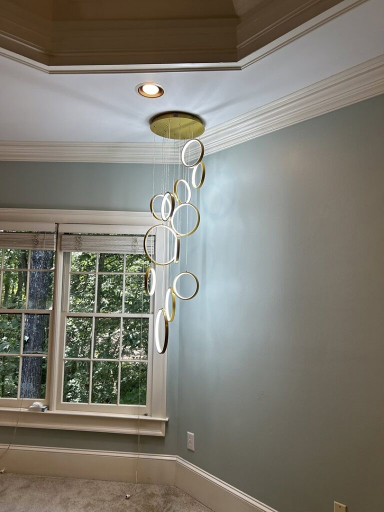 Modern vertical pendant light fixture with glowing rings installed by Perfection Lighting, Design, and Installations in Atlanta, GA.