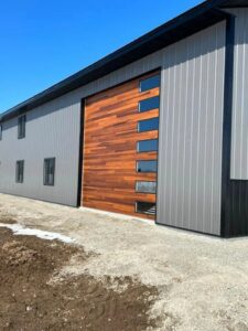 A modern vertical wood panel garage door with narrow windows installed on a commercial building by Overhead Doors Unlimited, LLC in Appleton, WI.