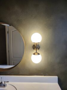 A modern wall sconce light fixture installed above a sink by ABS Electrical Services in Rogers, AR.