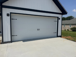 A modern white garage door with black decorative hardware on a new building by Phelps Dock and Door in Cave City, KY.