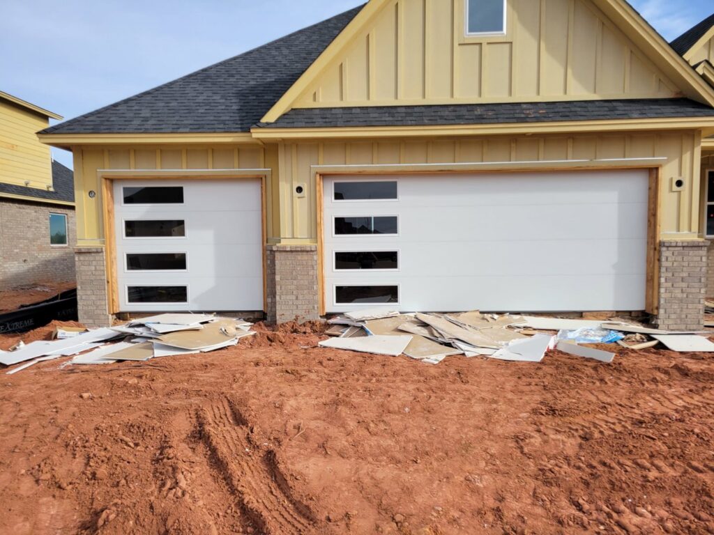 Two modern white garage doors with horizontal windows installed on a new construction home by CCM Overhead Doors in Oklahoma City, OK