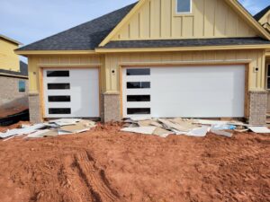 Two modern white garage doors with horizontal windows installed on a new construction home by CCM Overhead Doors in Oklahoma City, OK