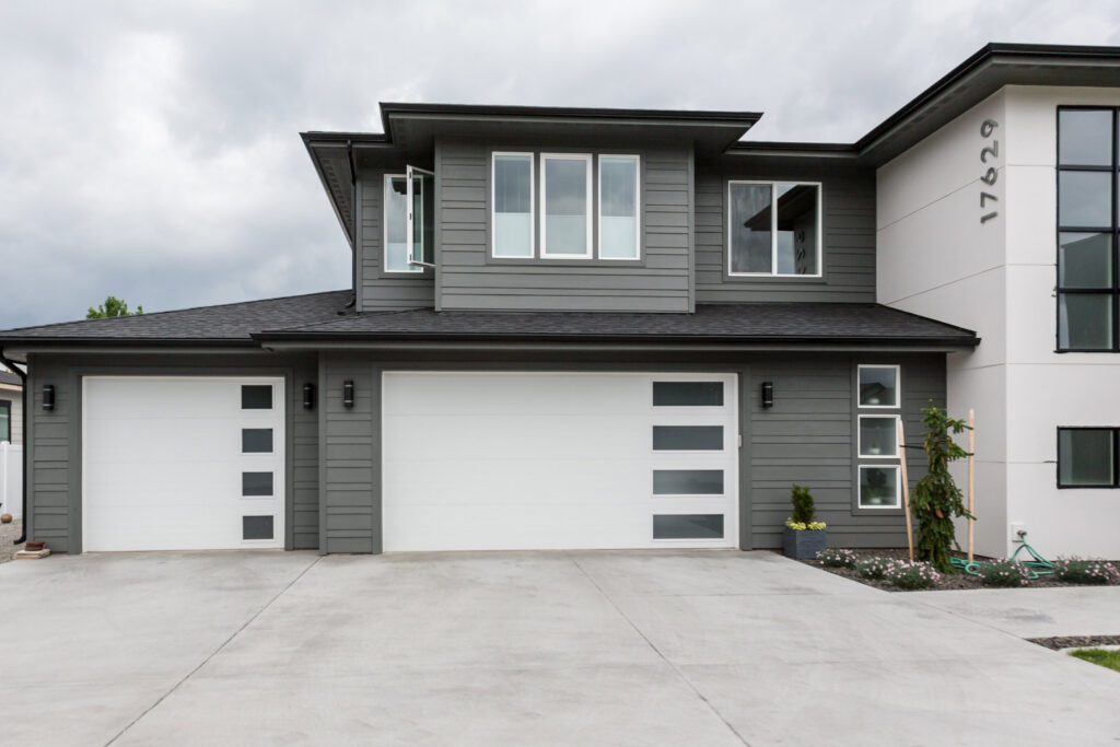 Modern white garage doors with vertical windows on a grey home, installed by Continental Door Company, Spokane Valley, WA.
