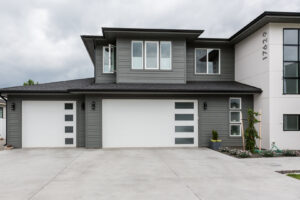 Modern white garage doors with vertical windows on a grey home, installed by Continental Door Company, Spokane Valley, WA.