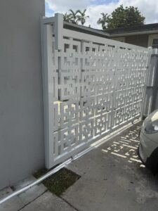 A modern white driveway gate featuring a unique geometric pattern installed by A Master Work Corp. in Hialeah, FL.