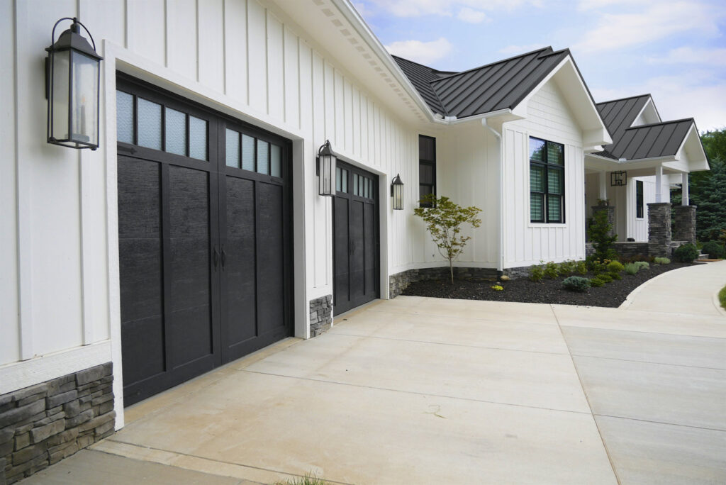 A modern white house with black trim and two black garage doors, installed by Precision Garage Door Service of Mobile in Mobile, AL.