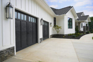 A modern white house with black trim and two black garage doors, installed by Precision Garage Door Service of Mobile in Mobile, AL.