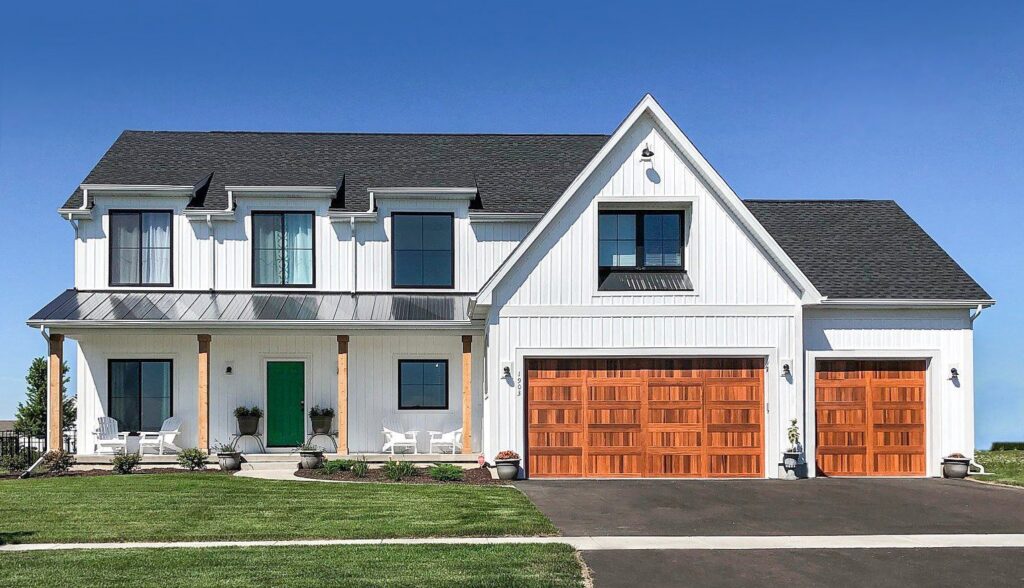 A modern white house featuring three stylish wooden garage doors installed by Monroe Overhead Doors in Monroe, LA.