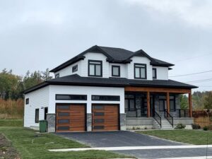 A modern white house showcasing two contemporary wooden garage doors with horizontal panels, installed by Monroe Overhead Doors in Monroe, LA.