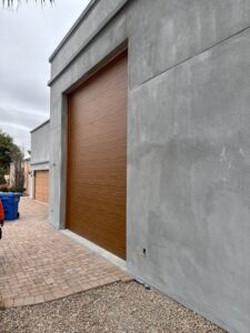 A modern wood-look garage door installed on a grey stucco building by Stapley Action Garage Door in Mesa, AZ.