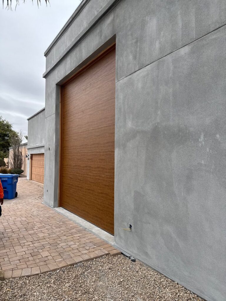 A modern wood-look garage door installed on a grey stucco building by Stapley Action Garage Door in Mesa, AZ.