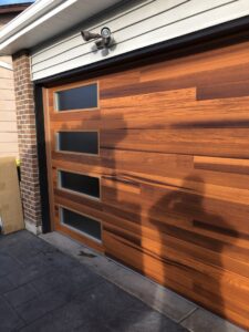A modern wood-look garage door with frosted windows installed by Colorado Garage Door Guy in Aurora, CO.