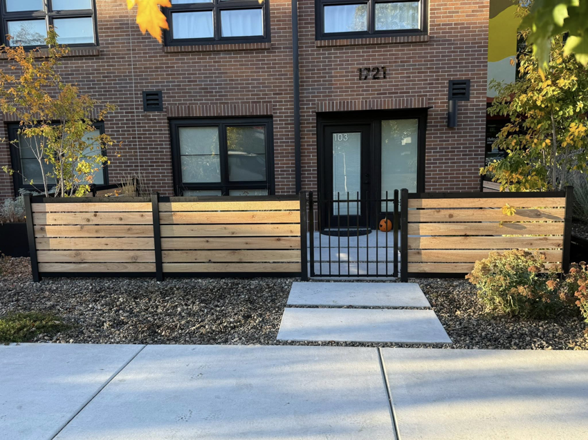 A newly installed modern wood and metal fence with a gate in front of a building by ZBros Fencing LLC in Boise, ID.
