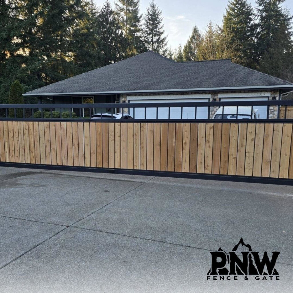 A modern wood and black metal sliding gate providing privacy for a residential property, installed by PNW FENCE in Lewiston, ID.