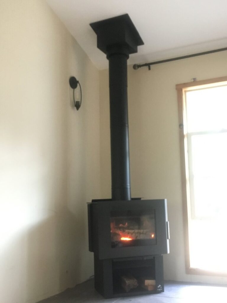 A modern wood stove with its flue pipe installed by Burning Bush Chimney Service in Wood Village, OR.