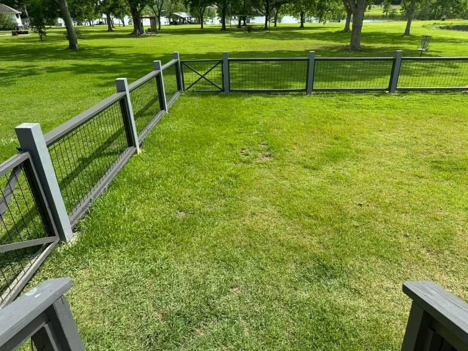 A modern wood and wire mesh fence with a gate in a residential yard by Deep South Services LLC in Biloxi, MS.