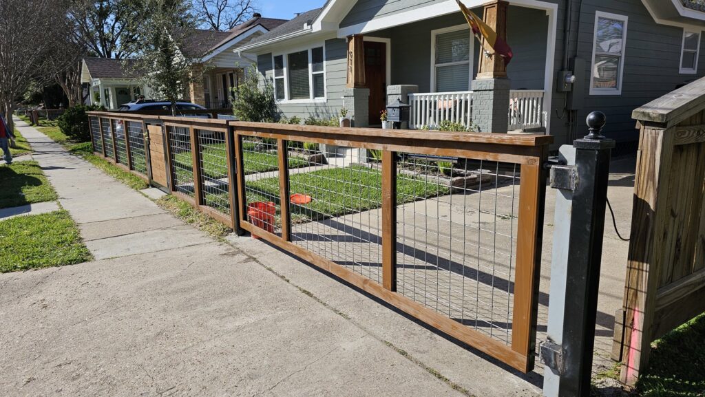 A modern wood and wire mesh fence installed along a sidewalk, providing a stylish boundary by Fence Builders of Houston, TX.