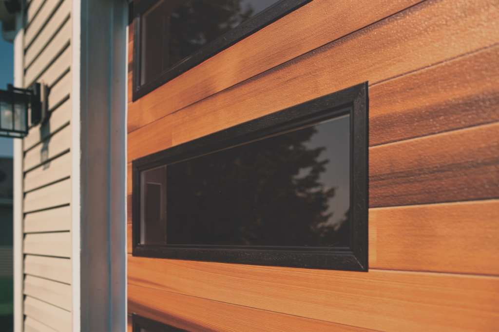 A close-up of a modern wooden garage door with black windows installed by Fireside Home Solutions in Portland, OR.