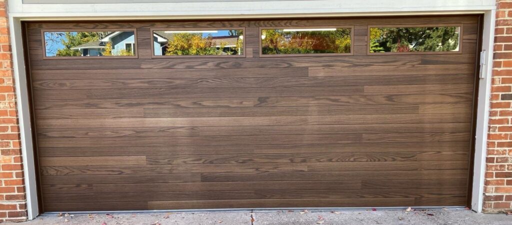 A modern wooden-style garage door with top row windows installed by Strongdoor garage in Denver, CO.