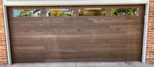 A modern wooden-style garage door with top row windows installed by Strongdoor garage in Denver, CO.