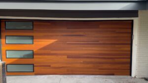 A modern wooden-style garage door with horizontal windows installed by Strongdoor garage in Denver, CO.