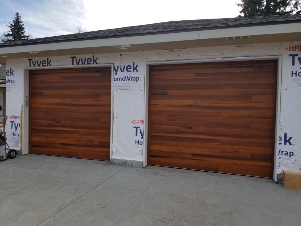 Installation of two modern wooden garage doors on a house under construction by Colorado Garage Door Pro's in Denver, CO