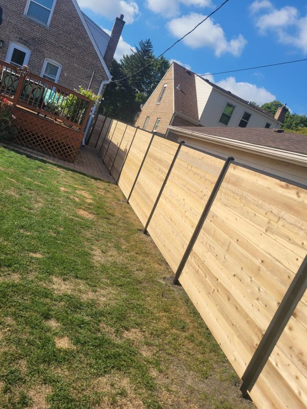 A modern wooden privacy fence with dark posts installed in a residential backyard by ALL STAR FENCE in Chicago, IL.