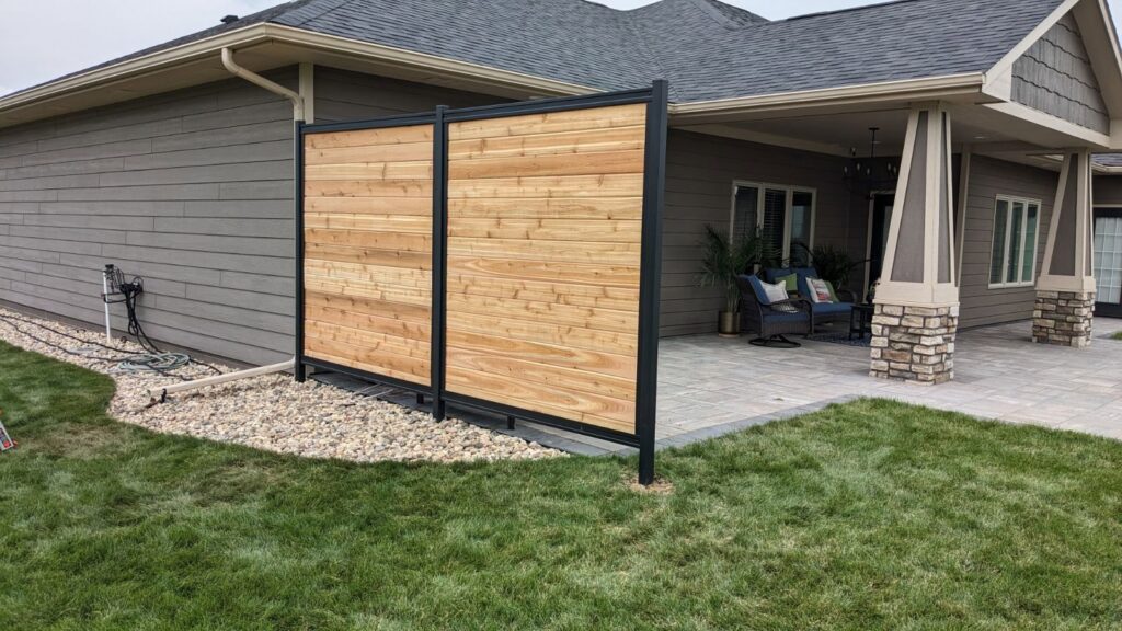 Two modern wooden privacy screens with black metal frames installed by Babb Custom Fence in Sioux Falls, SD.