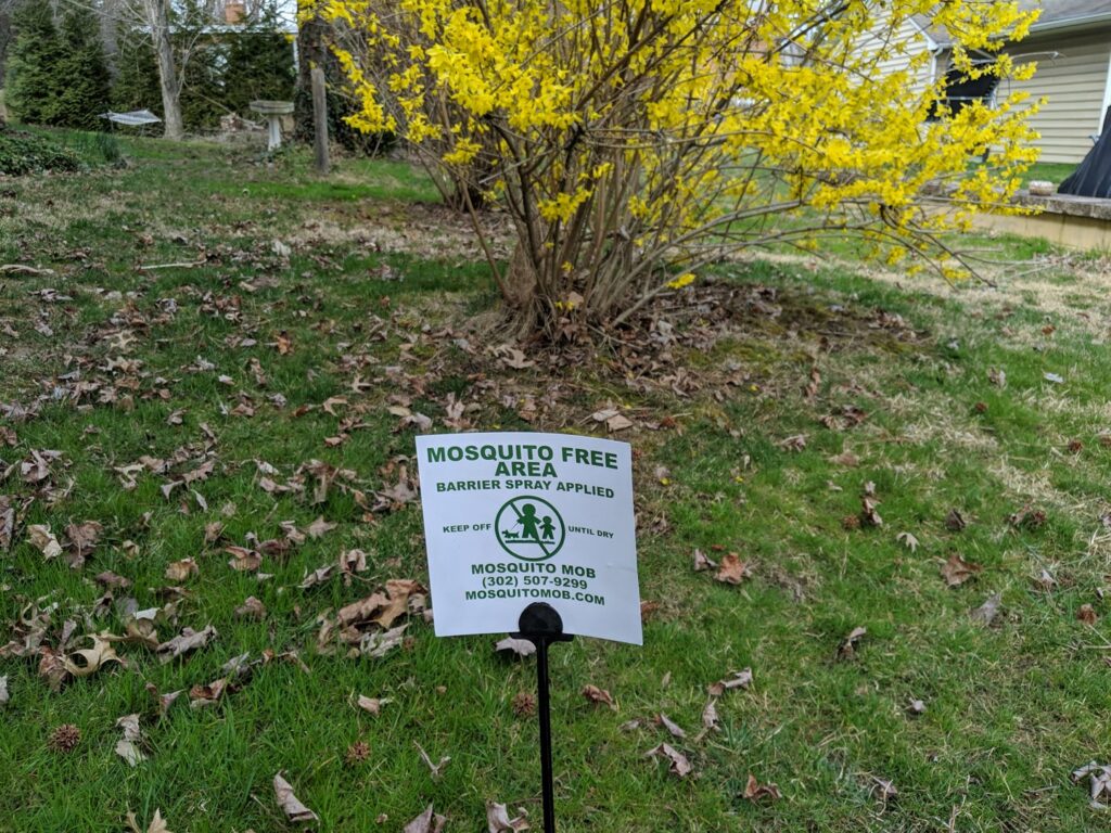 A "Mosquito Free Area" sign indicating barrier spray applied by Mosquito Mob in Wilmington, DE.