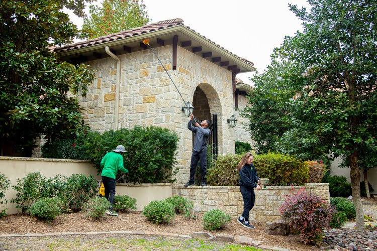 A Mosquito Joe team performing comprehensive pest control services around a home in Chattanooga, TN.