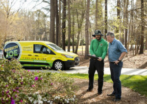 A Mosquito Joe technician consulting with a homeowner next to a branded service van in Newark, DE.