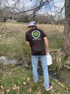 A Mosquito Joe of East Mississippi technician inspecting a water source for mosquito breeding in Meridian, MS.