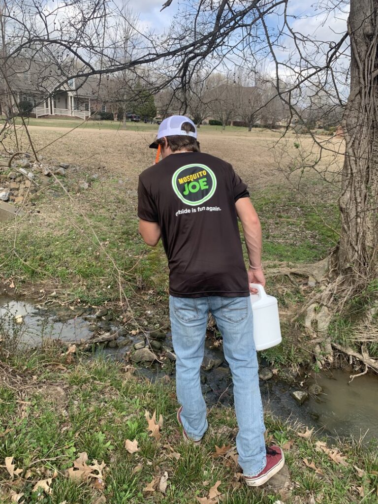 A Mosquito Joe of East Mississippi technician inspecting a water source for mosquito breeding in Meridian, MS.