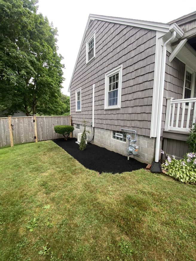 A neatly mulched flower bed beside a house, completed by Chaves Lawn Care in New Bedford, MA