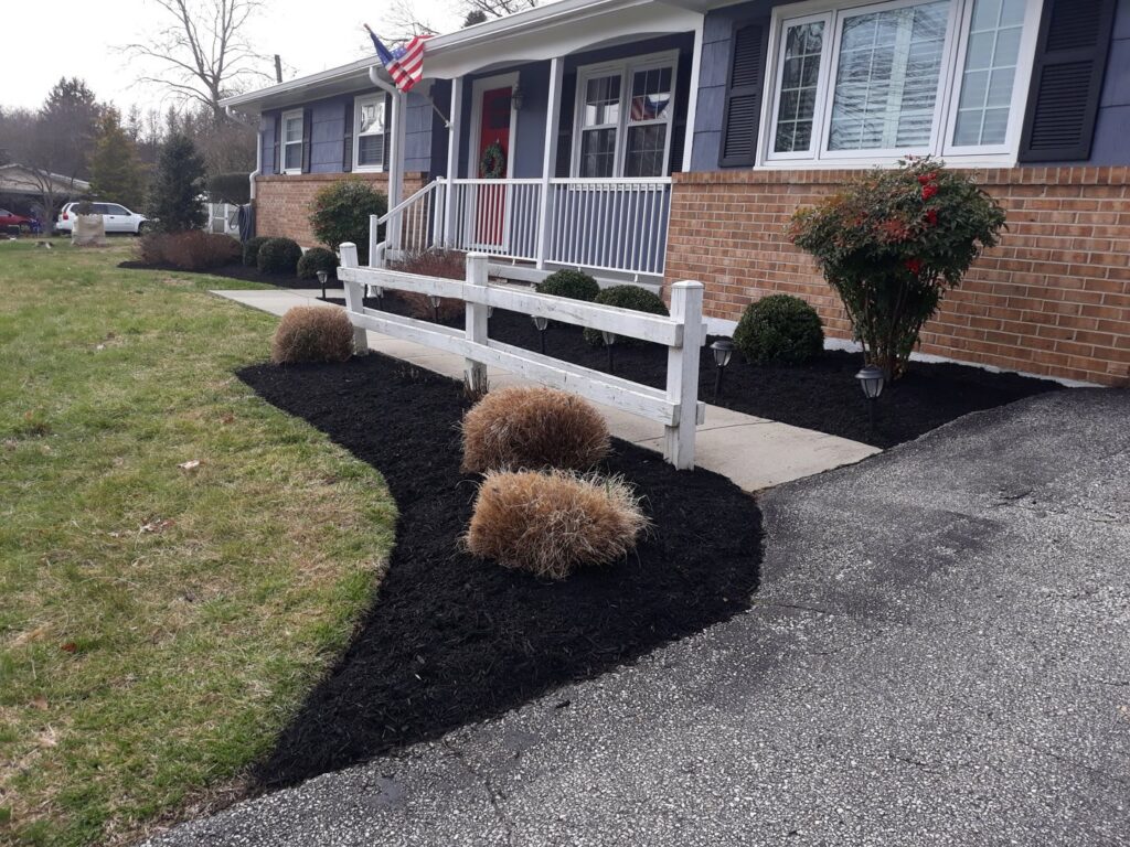 Neatly mulched garden beds along a driveway and fence by John's Lawn Care Service's in Saint Petersburg, FL