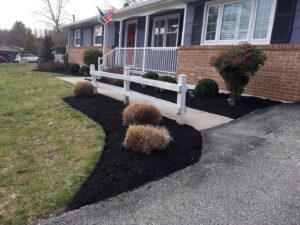 Neatly mulched garden beds along a driveway and fence by John's Lawn Care Service's in Saint Petersburg, FL