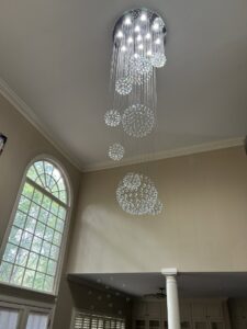 Installation of a stunning multi-level crystal chandelier in a high-ceiling room by Perfection Lighting, Design, and Installations in Atlanta, GA.