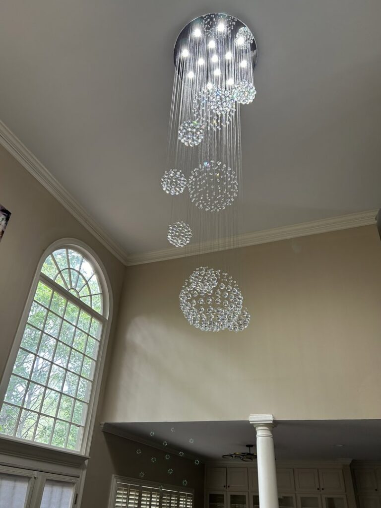 Installation of a stunning multi-level crystal chandelier in a high-ceiling room by Perfection Lighting, Design, and Installations in Atlanta, GA.