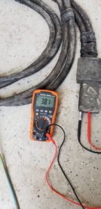 A multimeter testing thick electrical cables, demonstrating diagnostic work by J&L Electric Inc. in San Antonio, TX