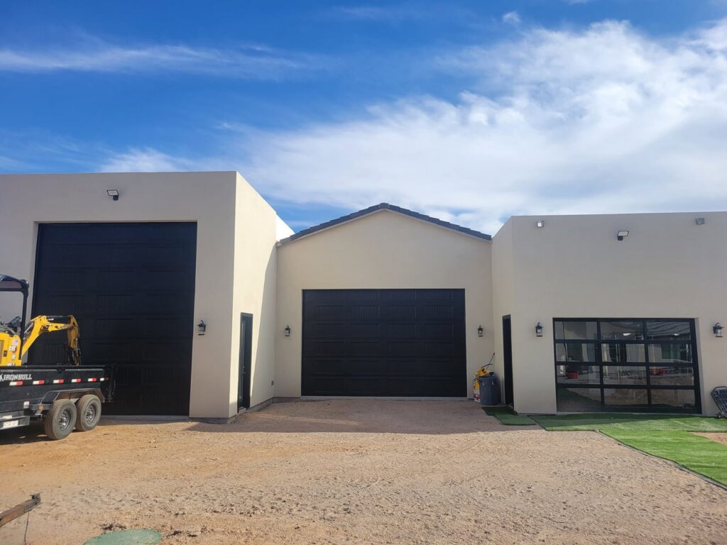 A building featuring multiple black garage doors, including one with modern glass panels, installed by JT's Overhead Doors in Gilbert, AZ.