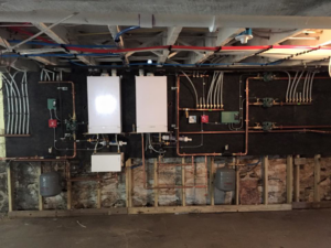 Multiple boilers, water heaters, and copper piping installed by Ausoli Grace Plumbing & Hvac in South Portland, ME.