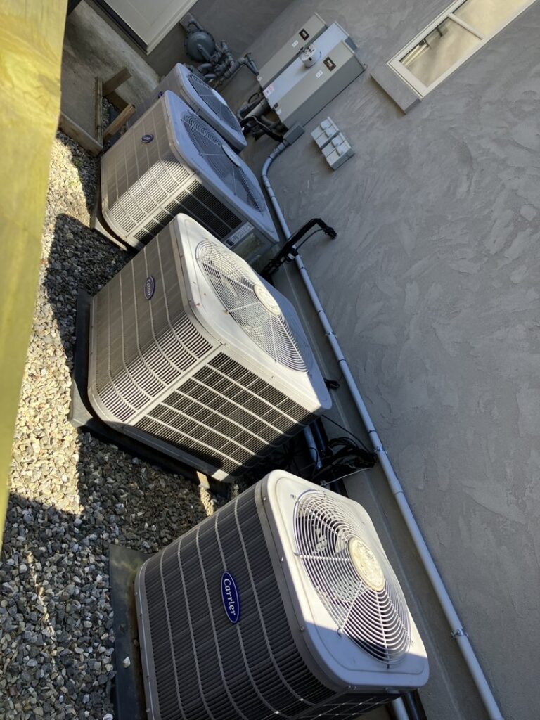 Multiple Carrier outdoor air conditioning units installed along a building wall by AVS Heating and Air Conditioning in Alexandria, VA.