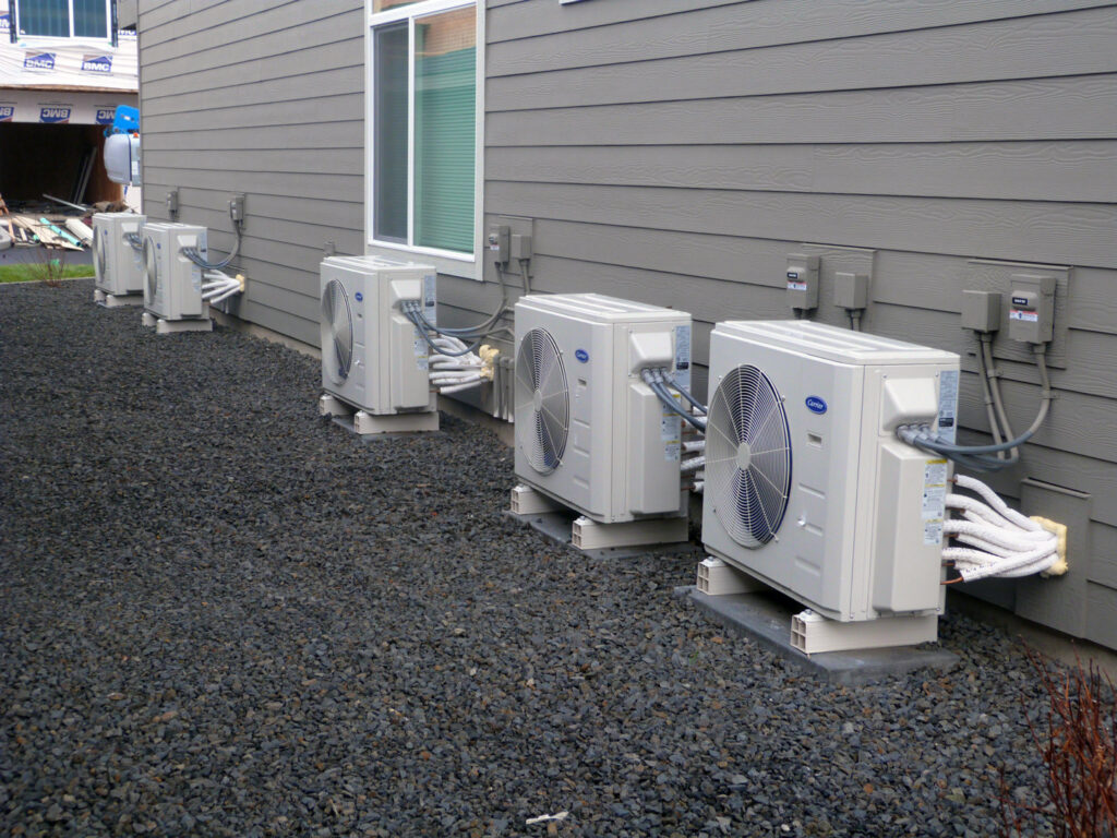 Multiple Carrier outdoor HVAC units installed along the side of a residential building by R&R Heating & Air Conditioning in Spokane, WA.