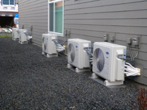 Multiple Carrier outdoor HVAC units installed along the side of a residential building by R&R Heating & Air Conditioning in Spokane, WA.