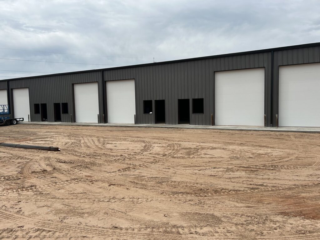 Multiple newly installed white commercial garage doors on a building by 405 Garage Pros in Edmond, OK.