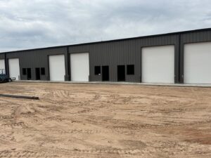 Multiple newly installed white commercial garage doors on a building by 405 Garage Pros in Edmond, OK.