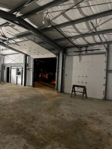 Multiple white commercial garage doors installed in a large metal building by Geaux Overhead Door in West Monroe, LA.
