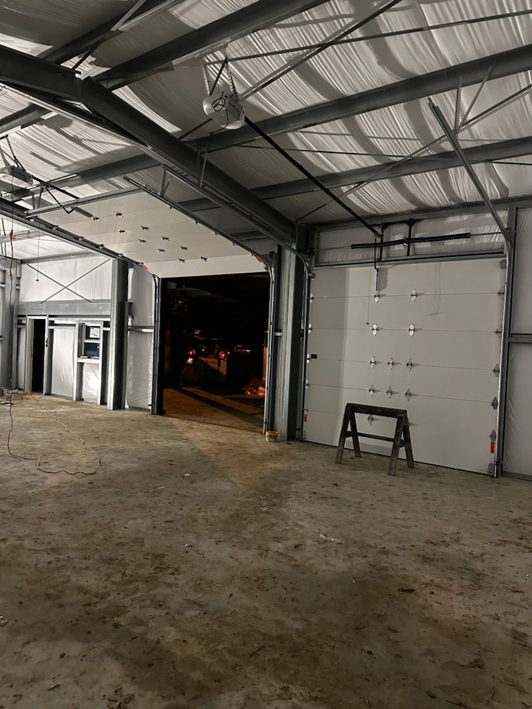 Multiple white commercial garage doors installed in a large metal building by Geaux Overhead Door in West Monroe, LA.